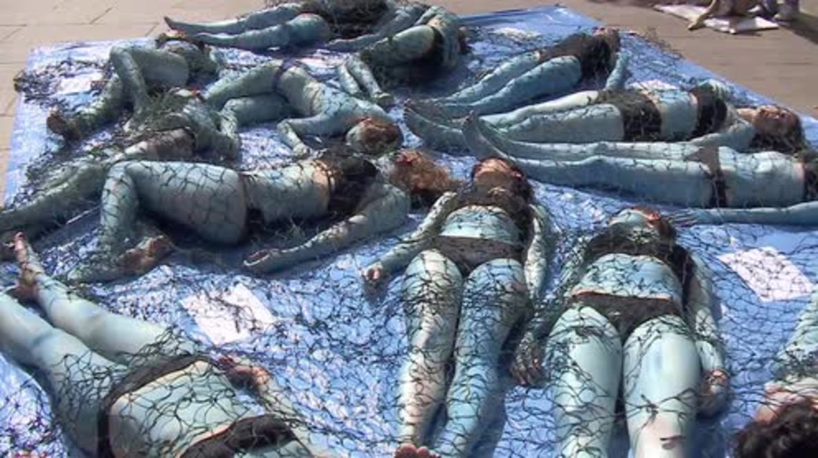 France: 'Netted' animal rights activists strip off in Paris to decry fishing industry