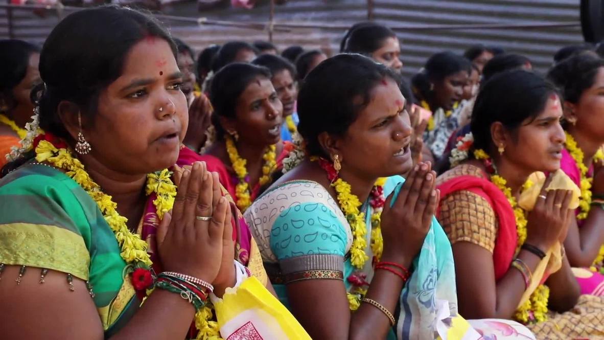 Mujeres comen del suelo con sus manos en la espalda durante ritual de fertilidad de la India