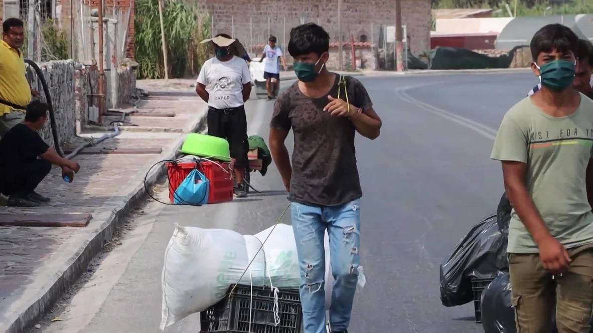 Greece: Migrants carry belongings to new camp as many still reluctant to move