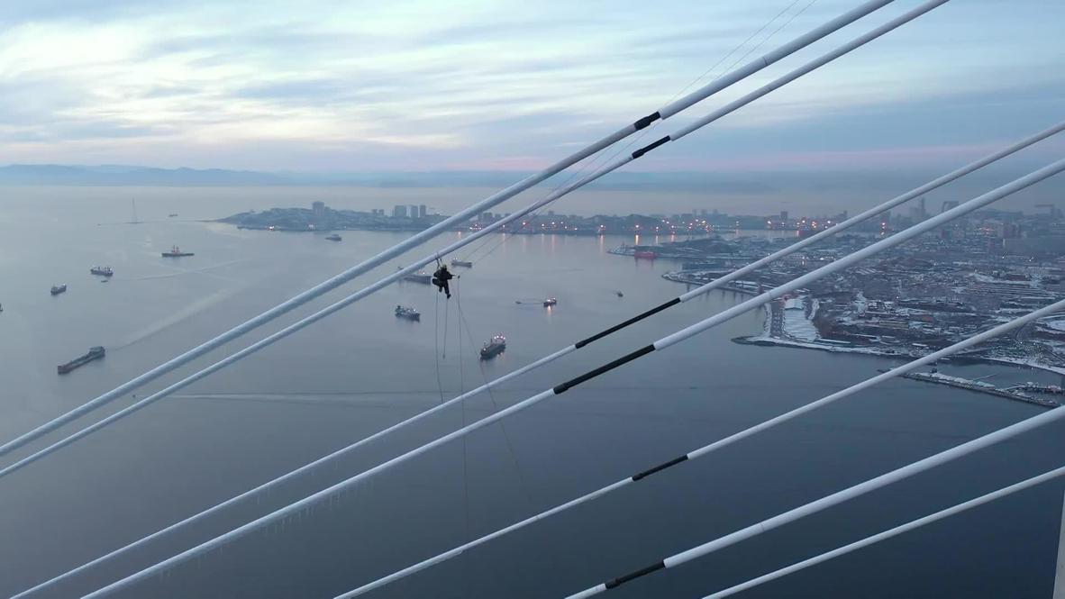 Russia: Alpinist cleans Russky bridge from ice after freezing rain *DRONE FOOTAGE*
